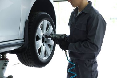 Tamirci araba servisinde lastik değiştiriyor, yakın plan.