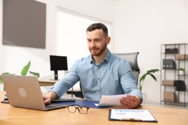 Ofiste masa başında çalışan yakışıklı adam.