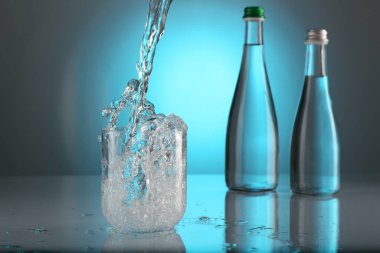 Açık mavi gradyan arkaplana karşı cam masaya su dökerek. Arka ışıklandırma