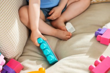 Evdeki kanepede tuğlalarla oynayan sevimli küçük çocuk, yakın plan.