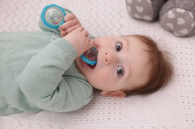 Evdeki beşiğinde çıngıraklı oyuncağı olan şirin bir bebek.