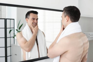 Banyodaki aynaya baktıktan sonra gülümseyen adam.