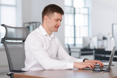 Ofisteki masada dizüstü bilgisayarda çalışan bir adam. Metin için boşluk
