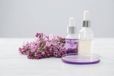 Lüks parfüm yapıyorum. Temel yağlar cam süslemede ve çiçekler beyaz ahşap masada, yakın plan.