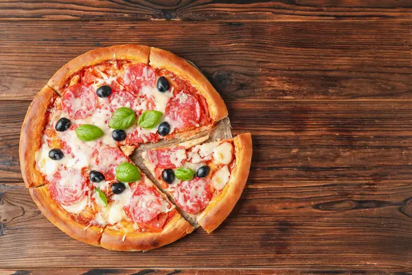 Tahta masada salamlı, peynirli, fesleğenli ve zeytinli lezzetli pizza. Metin için boşluk