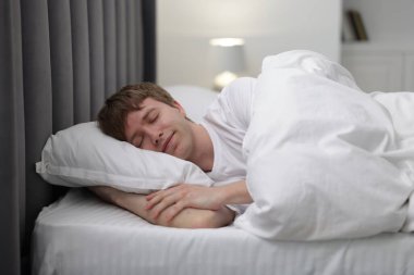 Genç adam yatağında uyuyor.