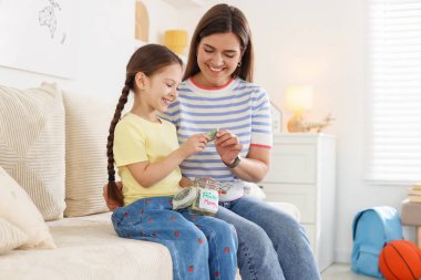 Anne kızına evdeki kanepede cep harçlığı veriyor.