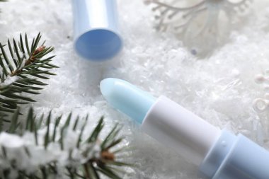 Nemlendirici dudak kremi, Noel dekorasyonu ve yapay kar üzerindeki köknar ağacı dalları, yakın plan. Kış bakımı
