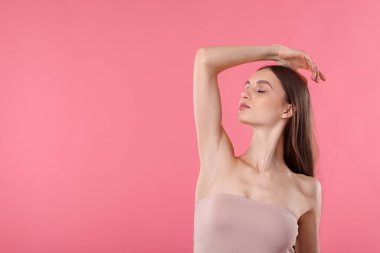 Pembe arkaplandaki epilasyondan sonra pürüzsüz cilt gösteren genç kadın, metin için boşluk