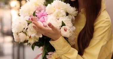 Şehir caddesinde elinde şakayık demeti olan bir kadın, yakın plan.