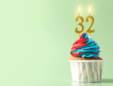 Açık turkuaz arka planda yanan mumlar, yazı için yer olan enfes bir kek. 32nci yaş günü veya diğer özel günler