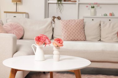 Oturma odasının içi rahat. İçinde çiçekler ve yumuşak kanepe olan yan masa.