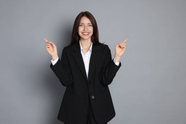 Gri arka planda takım elbiseli mutlu kadın