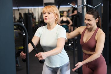 Spor salonunda profesyonel antrenör tarafından yönetilen son sınıf kadın makara makinesi eğitimi.