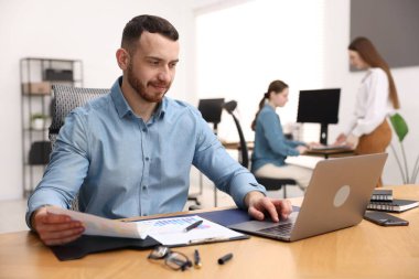 Ofiste masa başında çalışan yakışıklı adam.