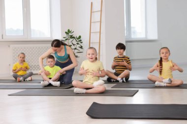 Yoga hocası grup derslerinde çocuklara yardım ediyor.