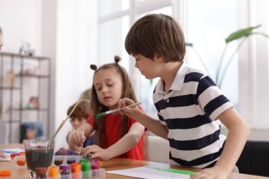Çocuklar kapalı mekanlarda resim yapıyor, seçici bir odak noktası var. Çizim yapmayı öğrenmek
