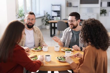İş arkadaşları öğle arasında ofiste sohbet ediyorlar.