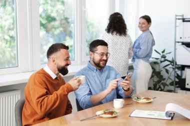 Ofiste öğle arasında iş arkadaşına akıllı telefondan bir şey gösteriyor.