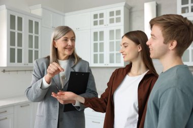 Gülümseyen emlakçı, mutfağın yeni sahibine evinin anahtarını veriyor.