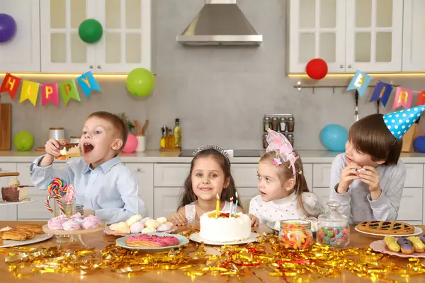 Masadaki çocuklar lezzetli pastalar ve farklı ev yemekleri yapıyorlar. Sürpriz parti.