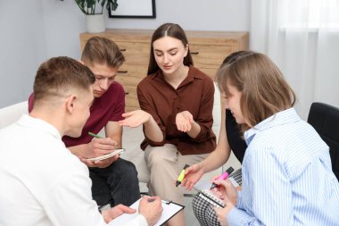 Yaşam koçluğu dersi sırasında not defterlerine yazı yazan bir grup insan.