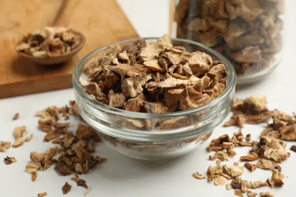 Kuru hindiba kökleri kasede, kavanoz ve kaşık beyaz masada, yakın plan.