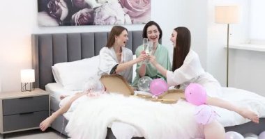 Pijama partisi. Evde pizza bardakları tokuşturan mutlu arkadaşlar.