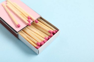 Açık mavi arka planda kibrit ve kutu, yakın plan. Metin için boşluk