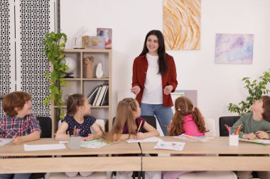 Çocuklara resim dersinde resim öğreten bir kadın.