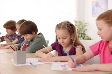 Çocuklar kapalı mekanlarda resim yapıyor, seçici bir odak noktası var. Çizim yapmayı öğrenmek