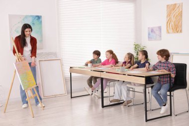 Çocuklara resim dersinde resim öğreten bir kadın.