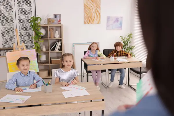 Çocuklara resim yapmayı öğreten kadın kapalı alanda resim dersi veriyor, seçici bir odak.