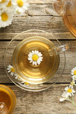 Cam bardakta nefis papatya çayı, taze çiçekler, bal ve çaydanlık ahşap masada, düz uzanmış