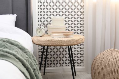 Çalar saati, kitapları ve yatağın yanında dekorasyonu olan yan masa.