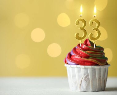 Sarı zemin üzerinde yanan mumlar, bulanık ışıklar ve yazı için yer olan enfes bir kek. 33. yaş günü veya diğer özel günler