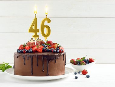 Meyveli lezzetli çikolatalı pasta ve yanan numaralar beyaz masada mumlar, mesaj için yer. 46. yaş günü ya da diğer özel günler