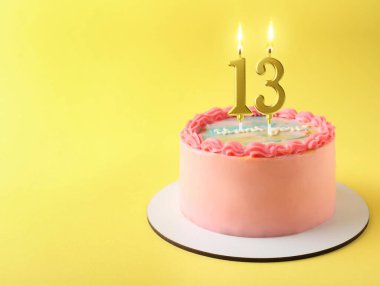 Sarı arka planda yanan mumlarla nefis bir pasta, mesaj için yer var. 13. yaş günü veya başka özel bir gün.