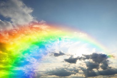 Mavi gökyüzünde parlak gökkuşağı güneşli bir günde bulutlarla