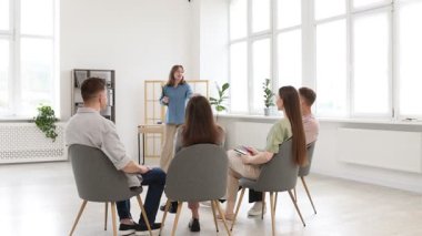 Akıl hocası ve grup insan içeride yaşam koçluğu dersinde toplantı yapıyorlar.