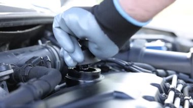 İşçi motor yağını teneke kutudan araba motoruna boşaltıyor.