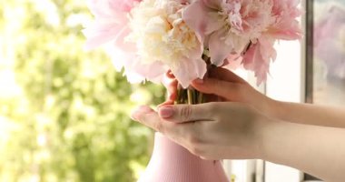 Pencerenin pervazına güzel şakayıklar koyan kadın, yakın plan.