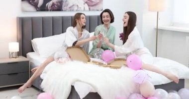 Pijama partisi. Evde pizza bardakları tokuşturan mutlu arkadaşlar.