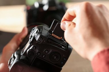 Bir adam fotoğraf makinesine SD bellek kartı yerleştiriyor.
