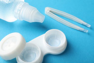 Mavi arkaplanda kontak lensler, çözüm ve cımbızlar, yakın plan