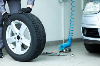 Tamirci araba servisinde lastik değiştiriyor, yakın plan.