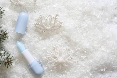 Nemlendirici dudak kremi, Noel dekorasyonu ve yapay kar üzerinde köknar ağacı dalları. Metin için boşluk