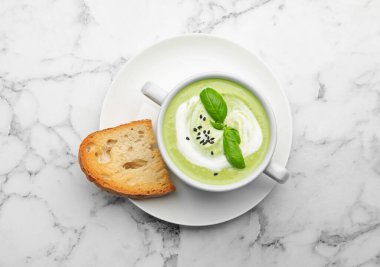 Fesleğenli bezelye kremalı çorba beyaz mermer masada servis edilir.