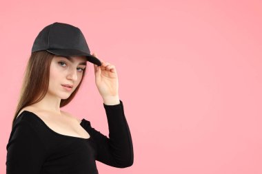 Pembe arka planda şık beyzbol şapkalı güzel bir kadının portresi. Metin için boşluk