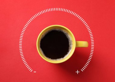 Kırmızı arka planda kahve ve güç göstergesi ölçeği, üst manzara. Maksimum alanı gösteren bardak sapı. Kafeinin enerji özelliği